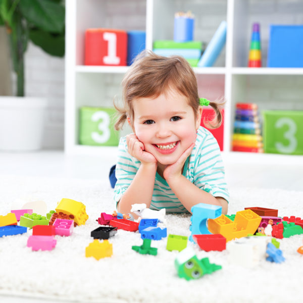 happy child girl laughing and playing with toys constructor